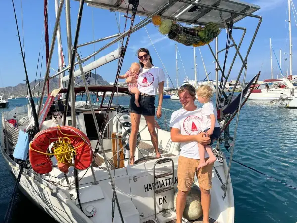Famille souriante sur un voilier, prête pour une aventure transatlantique à voile.